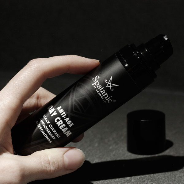 Black Spatanic anti-age day cream airless bottle in hand.