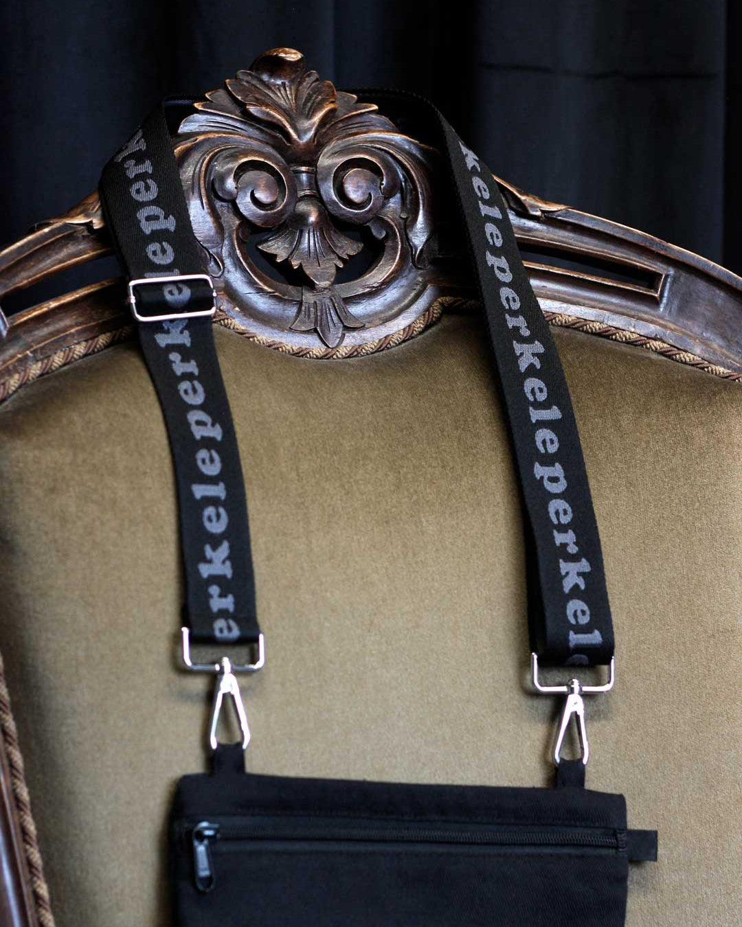 Decorative frame with ornate design and 'perkele' purse strap on a dark background