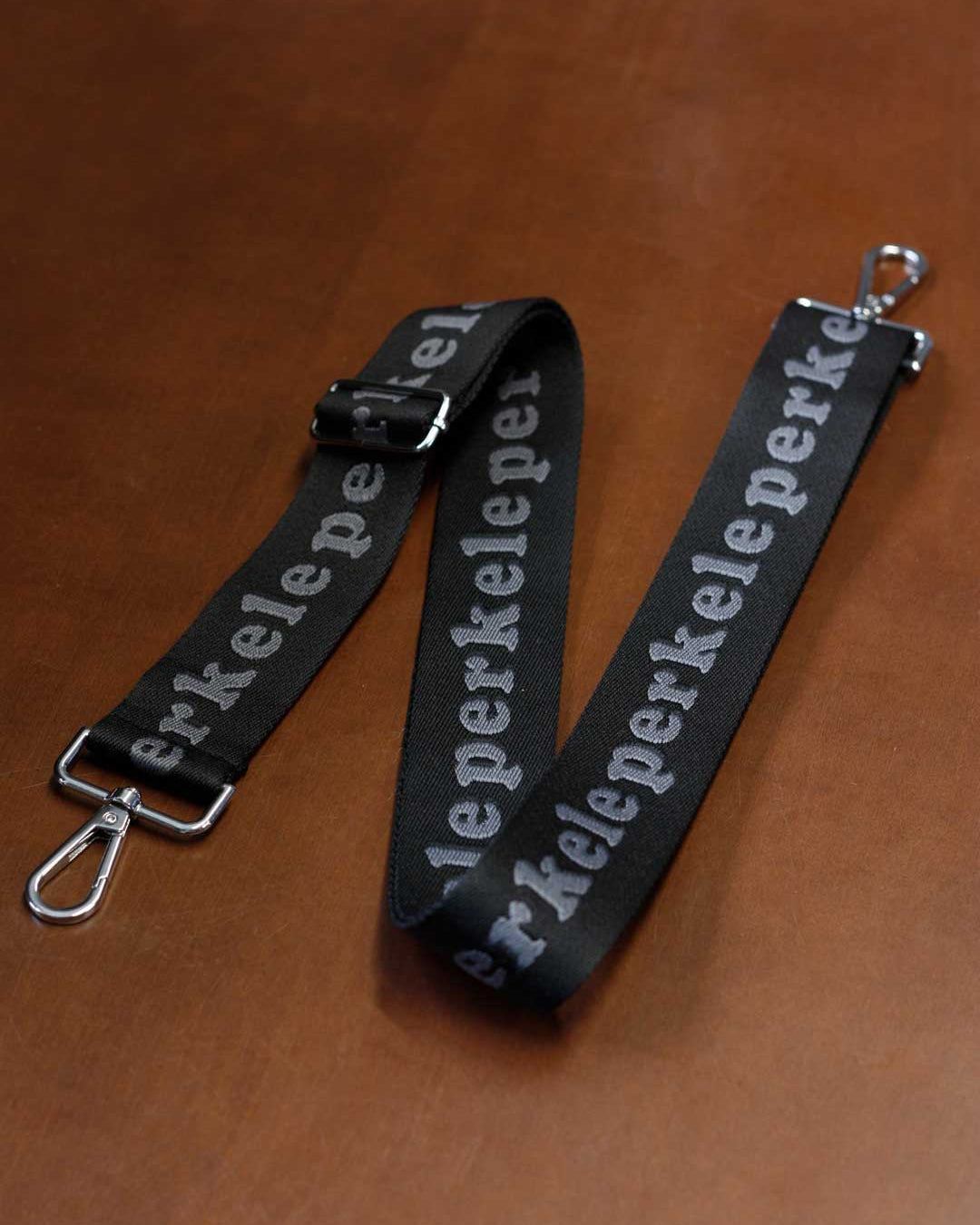 Black strap with 'perkele' text on a brown background