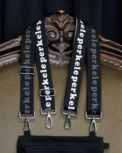 Black straps with 'perkele' text hanging on a decorative chair.