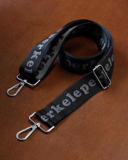 Black strap with silver hardware on a brown surface
