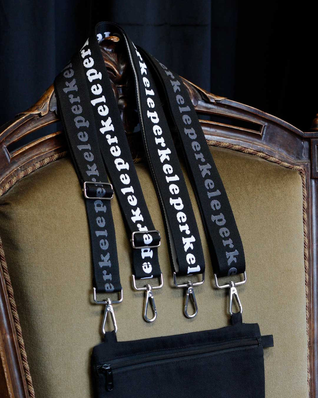 Black straps with 'perkele' branding hanging on a decorative chair.