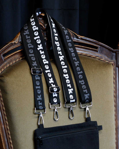 Black straps with 'perkele' branding hanging on a decorative chair.
