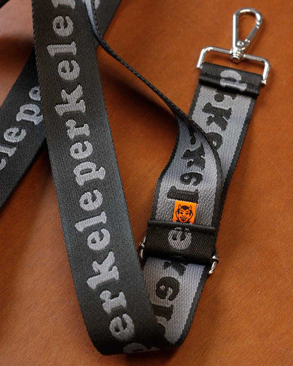 Gray strap with 'perkelel' branding on a wooden surface
